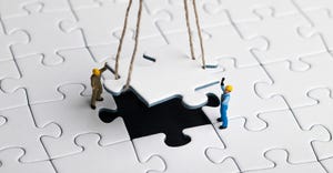 miniature workmen lowering puzzle piece into puzzle
