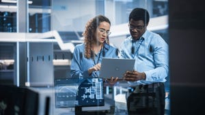 man and woman looking at tablet in manufacturing environment