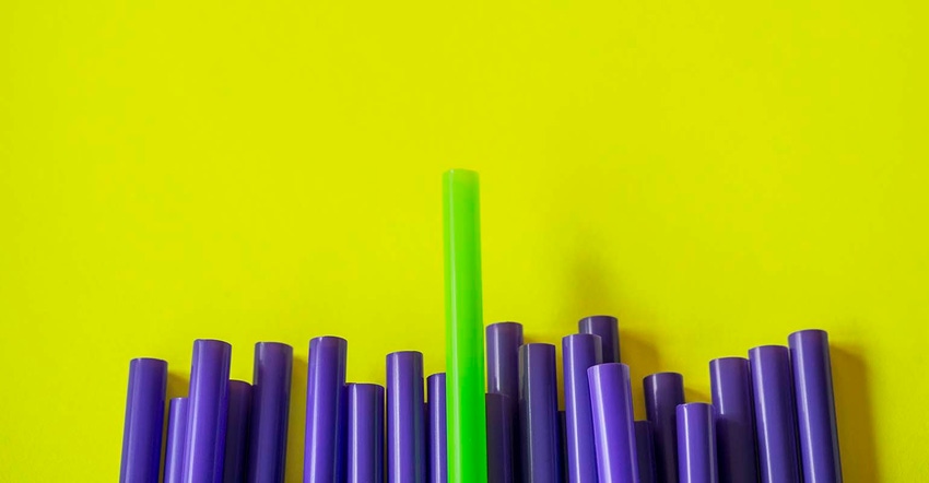 green drinking straw amid several purple ones