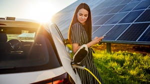 Young woman charging electric car with solar panels in background