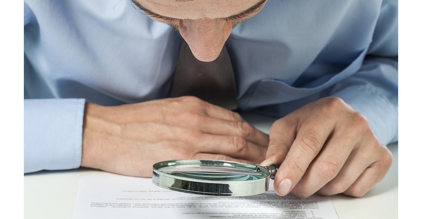 legal aide reviewing document with magnifying glass