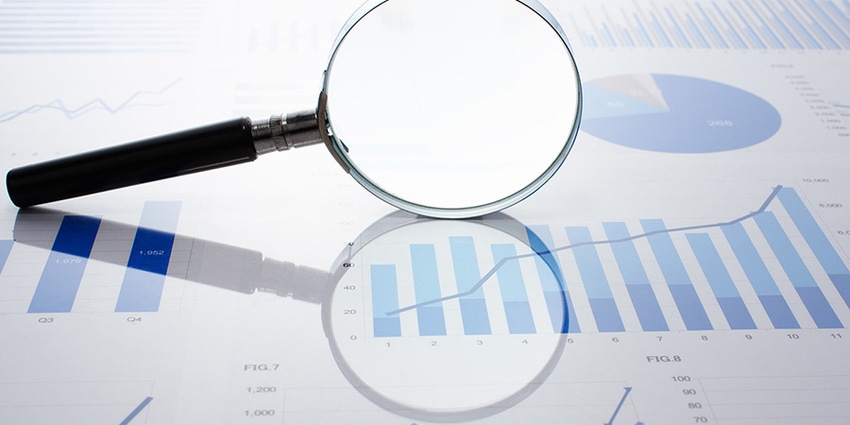 magnifying glass lays on on top of business/financial charts