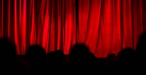 closed theater curtain with silhouette of audience