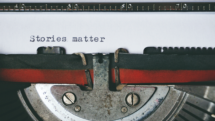 The words "stories matter" are typed on a sheet of paper that is still in a typewriter. 