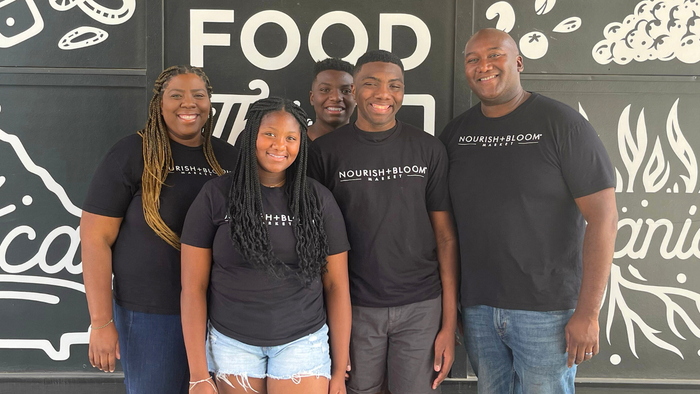 All five members of the Hemmings family pose for a photo in front of a decorated outside wall of their store. All five members of the Hemmings family pose for a photo in front of a decorated outside wall of their store.