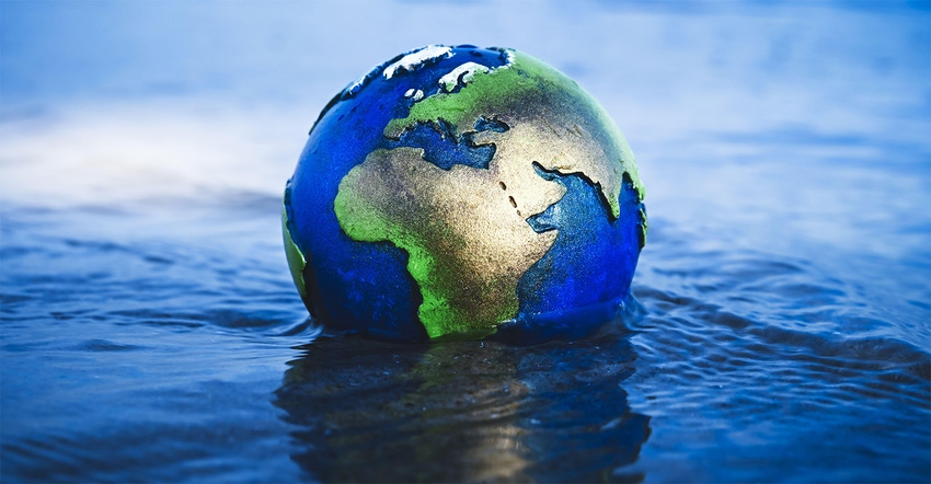 A globe is floating in blue water to illustrate climate change and the rise of the oceans.