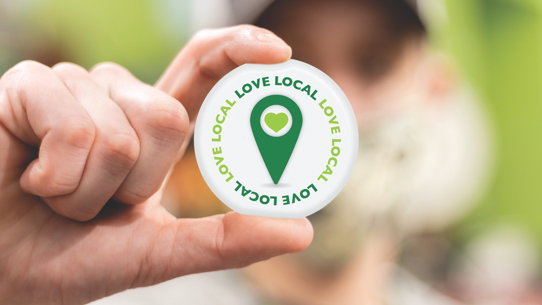 A hand holding a button that says Local