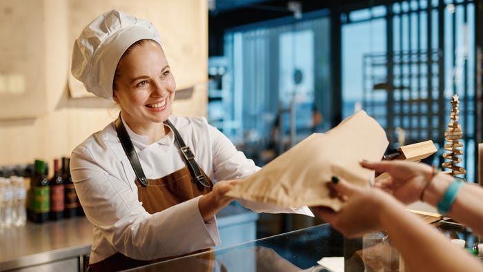 Food service refers to companies, institutions and businesses that serve meals prepared outside the home. A baker gives a package to a customer in a cafe.