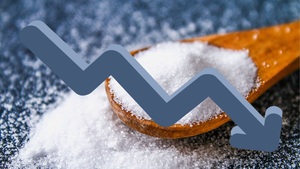 A downward-pointing blue arrow in front of a spoonful of table salt on a blue countertop illustrates the goal of reducing sodium in packaged foods. A downward-pointing blue arrow in front of a spoonful of table salt on a blue countertop illustrates the goal of reducing sodium in packaged foods.