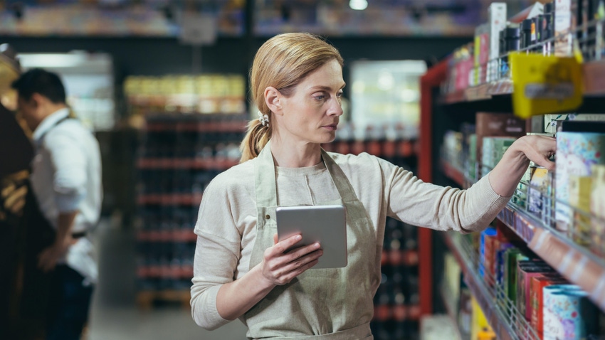 Female grocer takes inventory of the CPG foods in her store. 
