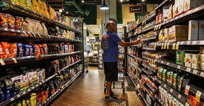 Independent grocers man walking grocery store aisle