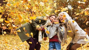 Three generations of women, playing in the autumn leaves, have different health needs.