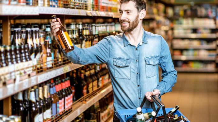A man wearing a denim shirt holds a bottle of nonalcoholic wine to read the label. Credit: Canva A man wearing a denim shirt holds a bottle of nonalcoholic wine to read the label. Credit: Canva