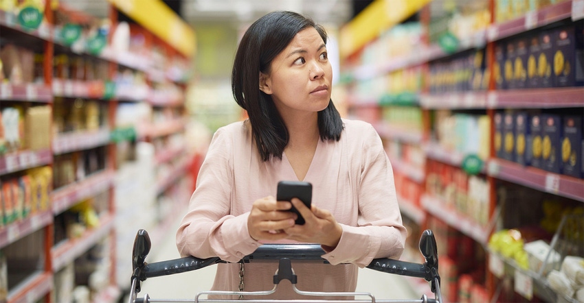 A woman shopping with a calculator looking concerned about grocery prices | Market Overview: Inflation complications persist 