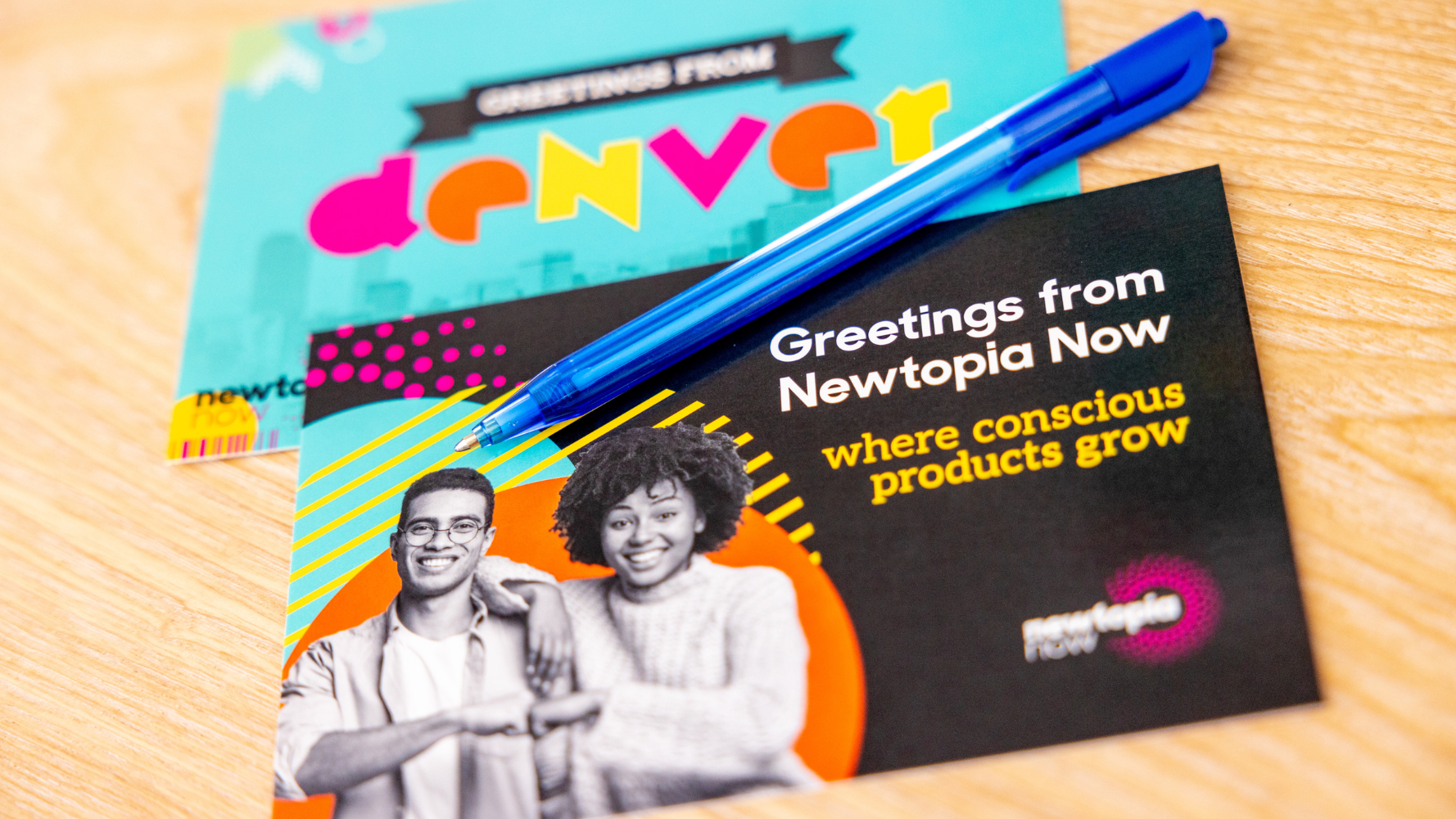 Two postcards, one reads &quot;Denver&quot; the other reads &quot;Newtopia Now&quot; 