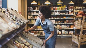Black, female grocery store owner stocks product in her small store
