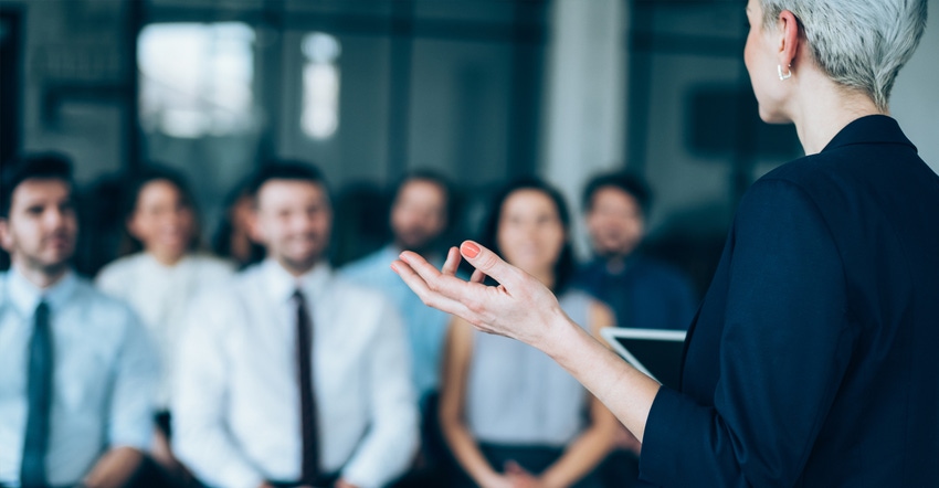 Woman speaking to a group of men