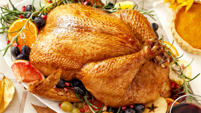 A roast turkey on a white platter, with a pumpkin pie nearby on a table decorated for an autumn holiday. A roast turkey on a white platter, with a pumpkin pie nearby on a table decorated for an autumn holiday.