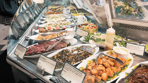 A variety of prepared salads, side dishes, fish and meats is showcased on white platters in a retail food service display.   A variety of prepared salads, side dishes, fish and meats is showcased on white platters in a retail food service display.