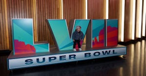 A young fan poses in front of a Super Bowl LVII sign.