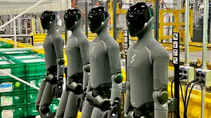 A row of four Figure humanoid robots in their charging docks A row of four Figure humanoid robots in their charging docks