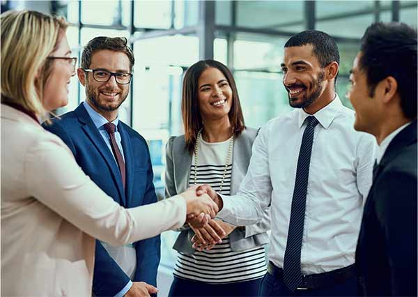 A group of five business colleagues from different cultures, two of them shaking hands