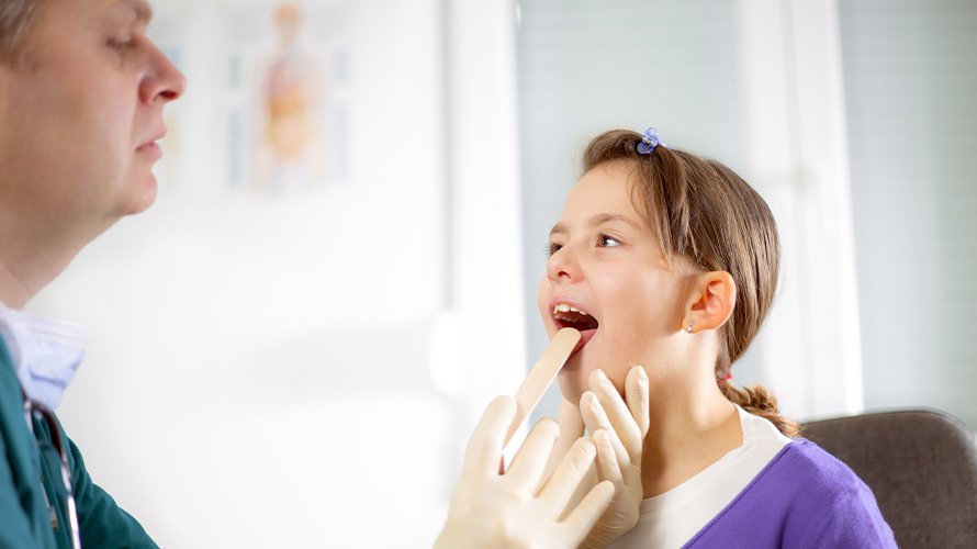 Doctor revisando a niña con faringitis