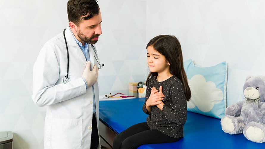 Doctor revisando a niña con dolor en el pecho
