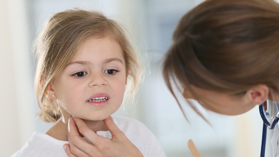 Doctora revisando garganta de niña pequeña