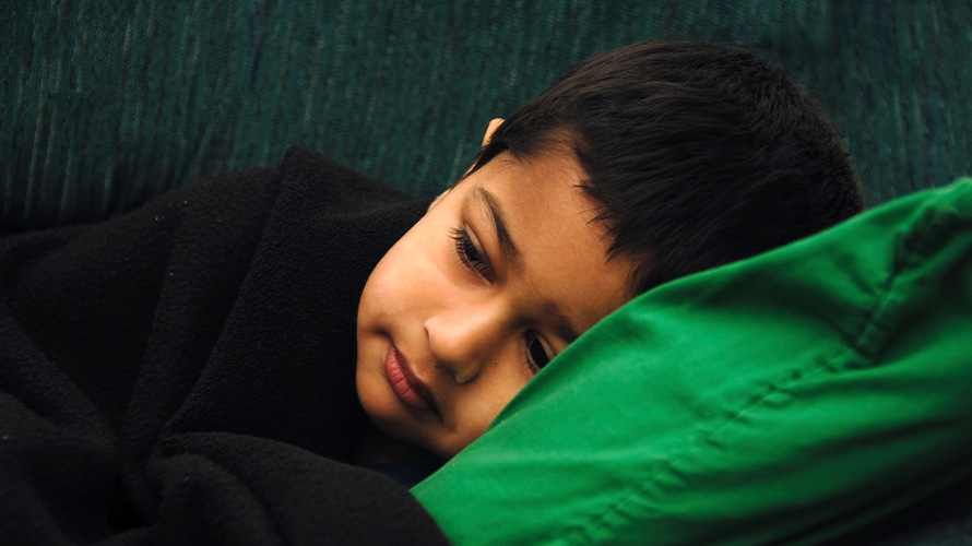 Niño recostdo sobre cama con resfriado