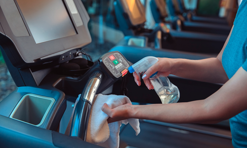 Persona adulta limpiando maquinas de gimnasio.png