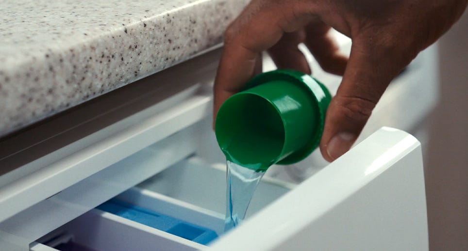 Dettol Laundry Sanitiser being poured into a washing machine drawer.