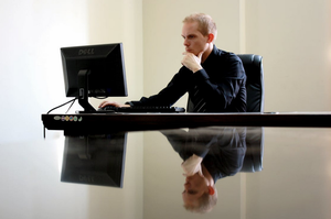 Man sitting at table in front of computer monitor