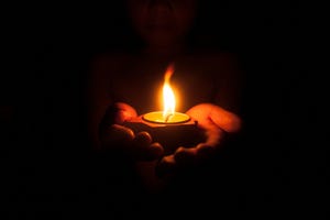 Hands holding candle in the dark