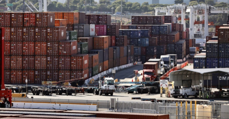 Trucks are seen by piled-up shipping containers at the port of Los Angeles, CA, Oct. 29, 2021. Port congestion has been a