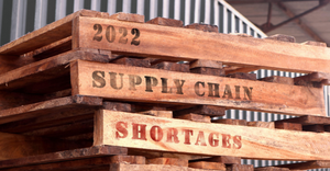 A photo of shipping pallets with the text: 2022 supply chain shortages printed on the sides of the pallets.