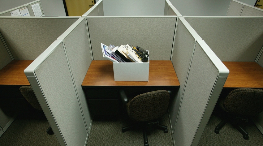 Photo illustration of company layoffs, empty cubicles with a box of employee belongings sitting on a desk.