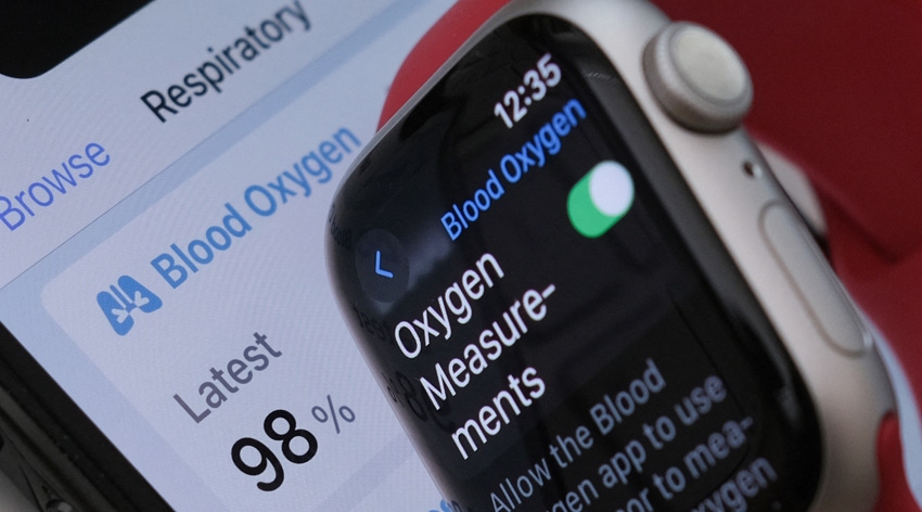 A photo illustration of an Apple Watch 9 displaying the blood oxygen measurement feature, with the connected mobile phone app in the shown background.