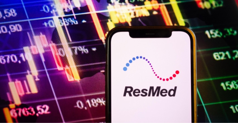 ResMed logo shown on a smartphone with stock market screen in the background