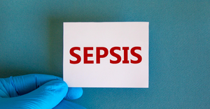Sepsis written on a card, held by a person wearing a medical glove.png