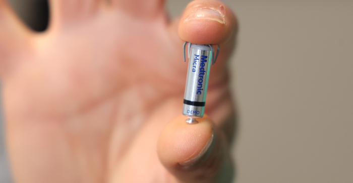 In this photo, a physician holds a Medtronic Micra Leadless Pacemaker between his thumb and forefinger (close-up of the device and the physician's hand).