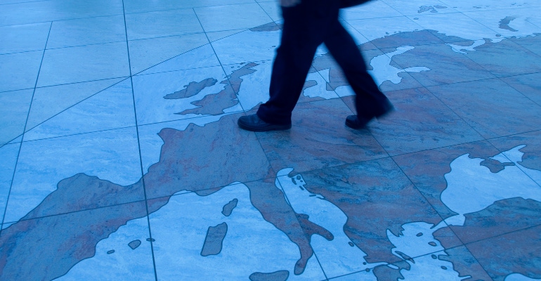 businessman walking across floor map of Europe