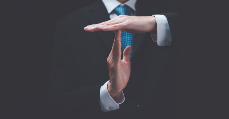 Man in business suit making the time out gesture with his hands.