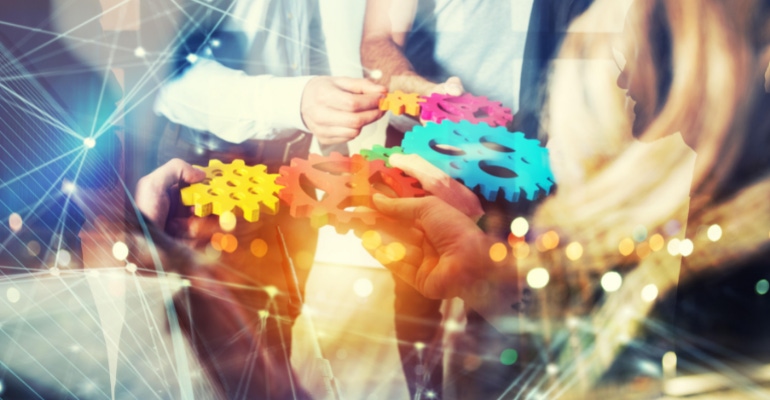 Double exposure image of a group of business people holding colorful gears to represent team work, partnership, and