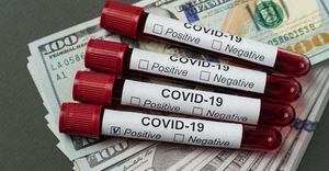 COVID-19 blood test samples on top of several $100 bills