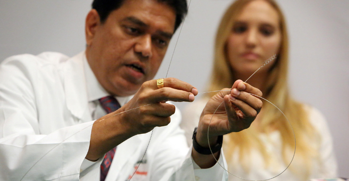 Dileep R. Yavagal, MD, Chief of UHealth Interventional Neurology, demonstrates how using Medtronic's Solitaire clot retrieval device, he was able to grab a clot inside of the blocked brain artery in stroke victim, Isabel Vinueza (shown in background). 