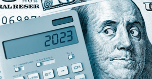 Benjamin Franklin on a hundred dollar bill looking at a calculator, which displays "2023"