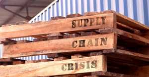 'Supply Chain Crisis', text written on piled up pallets illustrating the supply chain disruptions across industries,