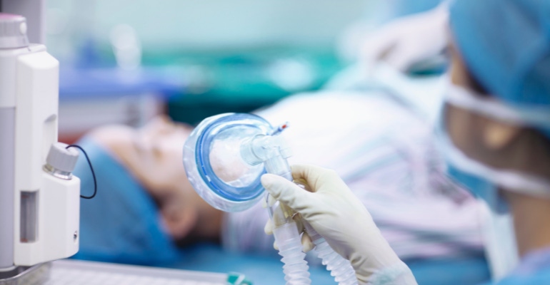 Nurse holding anesthesia mask in operating room