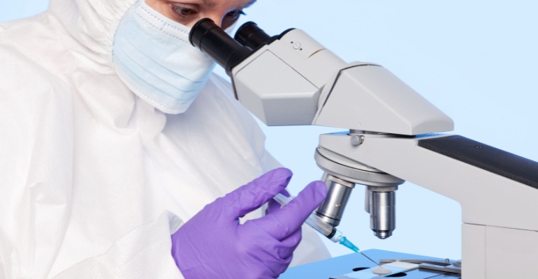 Photo of an embyologist examining a sperm sample through a stereo laboratory microscope